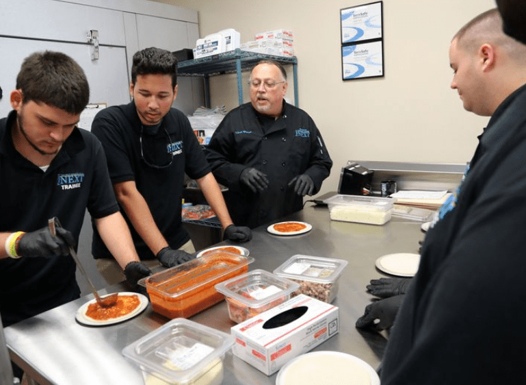 Chef Wayne Cooper guides Project Next trainees in making pizzas at the Palm Beach School for Autism in Lake Worth on Wednesday, Sept. 18, 2019. The school unveiled a new 10,000-square-foot kitchen extension, classroom, mock hotel room and more for culinary and hospitality students with autism.