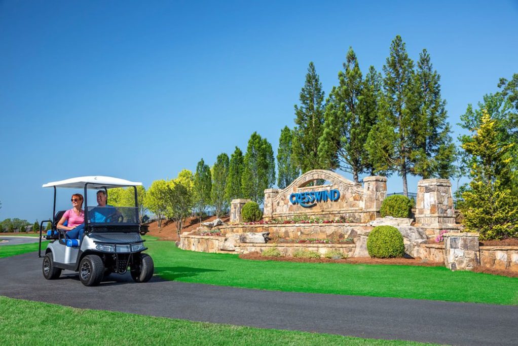 couple on golfcart riding in front of the Kolter Cresswind sign