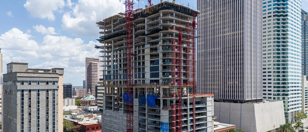 High-rise building under construction with cranes in city